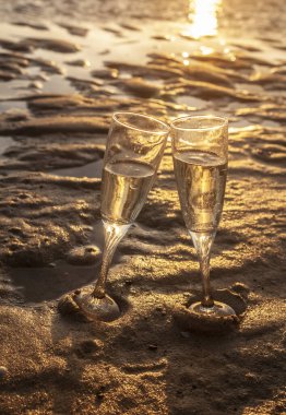 İspanya 'da gün batımında sahilde iki kadeh şampanya.