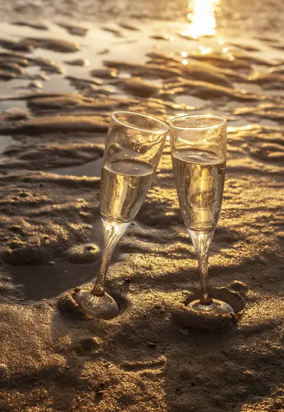 İspanya 'da gün batımında sahilde iki kadeh şampanya.