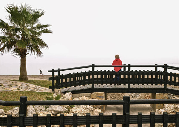 Young beautiful woman with a red coat in torremolinos beach
