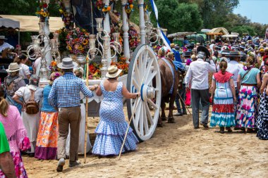 Tipik rociera kıyafetleri giymiş kadınlar, Rocio hac yolculuğuna Doana, Huelva, İspanya yolları boyunca öküz arabasının arkasında çıkıyorlar..