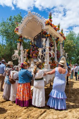 Tipik rociera kıyafetleri giymiş kadınlar, Rocio hac yolculuğuna Doana, Huelva, İspanya yolları boyunca öküz arabasının arkasında çıkıyorlar..