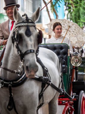 Fuengirola, İspanya. 09/23/2024. İnsanlar tipik Endülüs kostümleri giyip Fuengirola 'daki At Günü kutlamalarında klasik bir arabaya biniyorlardı..