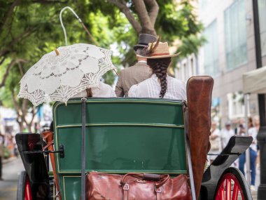 Fuengirola, İspanya. 09/23/2024. İnsanlar tipik Endülüs kostümleri giyip Fuengirola 'daki At Günü kutlamalarında klasik bir arabaya biniyorlardı..