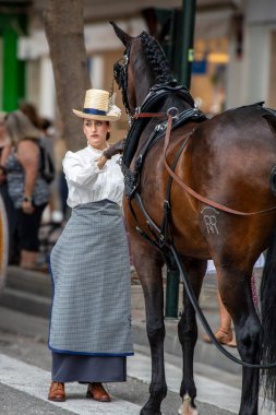 Fuengirola, İspanya. 09/23/2024. İnsanlar tipik Endülüs kostümleri giyip Fuengirola 'daki At Günü kutlamalarında klasik bir arabaya biniyorlardı..