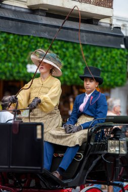 Fuengirola, İspanya. 09/23/2024. İnsanlar tipik Endülüs kostümleri giyip Fuengirola 'daki At Günü kutlamalarında klasik bir arabaya biniyorlardı..