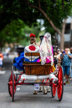 Fuengirola, İspanya. 09/23/2024. İnsanlar tipik Endülüs kostümleri giyip Fuengirola 'daki At Günü kutlamalarında klasik bir arabaya biniyorlardı..