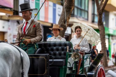 Fuengirola, İspanya. 09/23/2024. İnsanlar tipik Endülüs kostümleri giyip Fuengirola 'daki At Günü kutlamalarında klasik bir arabaya biniyorlardı..
