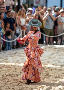09/20/2024. Fuengirola, Malaga, İspanya. Fuengirola 'da bir meydanda at günü kutlamalarında, pembe flamenko elbiseli ve şapkalı bir dansçı, bir sevillanas dansı sahnesi canlandırıyor..