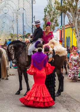 Fuengirola, Malaga, İspanya. 10/11/2024. Kovboy kostümü giymiş birkaç atlı ve Endülüs fırfırlı elbisesi Fuengirola 'nın fuar alanlarında at sürüyor..