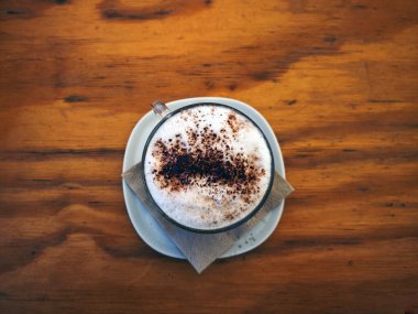Ahşap bir masada tarçınlı kapuçino kahve fincanı.