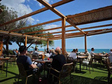 Fuengirola, Malaga, İspanya. 03/15/2025. Plaj barı turistlerle dolu. Güneşin tadını çıkarıyorlar..