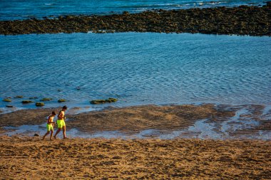Tarifa, Cadiz, İspanya. 27 Haziran 2025. Gün batımında Tarifa 'nın kumlu sahillerinde yürüyen çocuklar..
