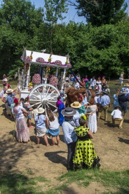 Almonte, Huelva, İspanya. 4 Haziran 2025. Geleneksel vagon, El Rocio 'nun kutsal yolculuğunun geçişi için Quema nehrinden geçerek dekore edilmiştir..