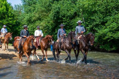 Huelva, Endülüs, İspanya. 4 Haziran 2025. Geleneksel Endülüs dalgalı elbiseler giymiş kadınlar geleneksel El Roco Bakiresi onuruna yapılan geleneksel kutsal yolculukta Quema Nehri 'nin karşı kıyısına geçerler..