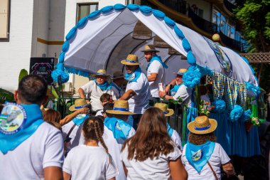 Fuengirola, Mlaga, İspanya. 28 Eylül 2025. Fuengirola Bakiresi 'nin kutsal yolculuğu için süslü arabaların arkasında geleneksel Endülüs kostümleri giyen geniş insan grupları..