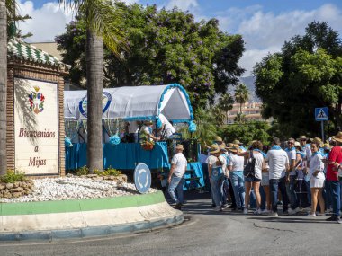 Fuengirola, Mlaga, İspanya. 28 Eylül 2025. Fuengirola Bakiresi 'nin kutsal yolculuğu için süslü arabaların arkasında geleneksel Endülüs kostümleri giyen geniş insan grupları..