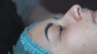 Kız kırışıklıkları azaltmak için besleyici bir kömür maskesi takıyor. Mavi baloncuk maskeli bir kadının yüzünü yakından çek. Karbonatlı baloncuk maskesi.