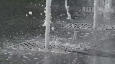 Kasaba meydanının ortasındaki çeşme güneşte ufalanan ve parlayan büyük su damlalarını fırlatıyor..