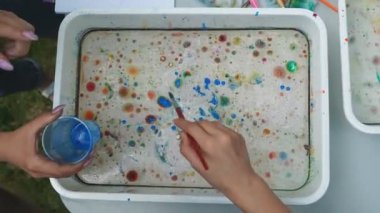 Suyun üzerine çok renkli suluboya damlaları. Küçük çocuklar için hafta sonu eğlencesi. Çocukların yaratıcılığının gelişimi.