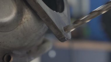 Araba servis istasyonunda metali delme işlemi. Delme aleti, egzoz sisteminin büyük bir metal bölümünde derin bir delik açar. Bir atölyede bir metal ürünü mekanik bir aletle delmek