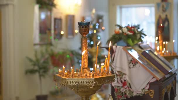 背景にぼやけた光を広げる寺院の砂の燃焼に挿入された照明ワックスキャンドル キリスト教会での礼拝の伝統について詳しく見る — ストック動画