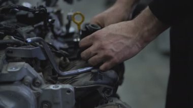 Bir araba hizmet merkezinde içten yanmalı bir motoru tamir etmek. Araba tamircisinin elleri oto tamir servisinde çalışıyor..