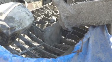 İnşaat alanındaki inşaatçılar yüzeyi beton ve küçük çakıl karışımıyla bir konut inşaatı alanının betonlaşması için döşüyorlar.
