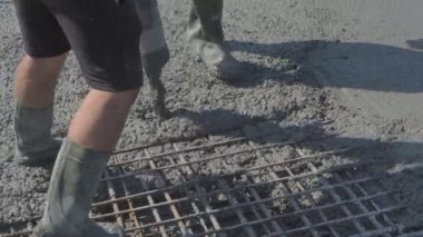 İnşaat alanındaki inşaatçılar yüzeyi beton ve küçük çakıl karışımıyla bir konut inşaatı alanının betonlaşması için döşüyorlar.