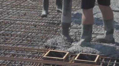 İnşaat alanındaki inşaatçılar yüzeyi beton ve küçük çakıl karışımıyla bir konut inşaatı alanının betonlaşması için döşüyorlar.