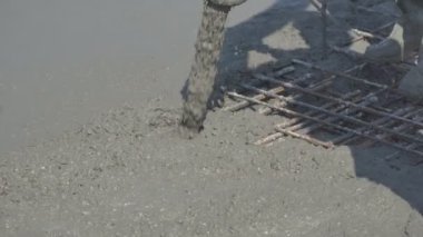 İnşaat alanındaki inşaatçılar yüzeyi beton ve küçük çakıl karışımıyla bir konut inşaatı alanının betonlaşması için döşüyorlar.