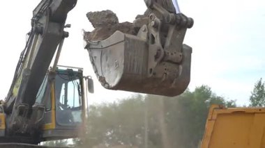 İnşaat atıklarını bir kamyonun arkasına yüklüyorlar. Büyük bir kazıcı kovası arkasına atık doldurur. Alanı boşaltıyorum..