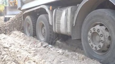 Kumlu toprağa sıkışmış büyük bir kamyonun tekerlekleri. Ağır kamyon düz ve sert zemine ulaşmak için büyük çaba harcıyor..