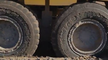 Kumlu toprağa sıkışmış büyük bir kamyonun tekerlekleri. Ağır kamyon düz ve sert zemine ulaşmak için büyük çaba harcıyor..
