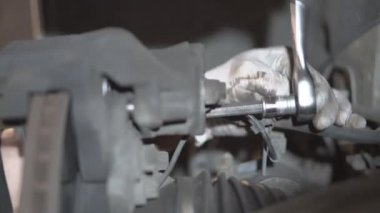 Bir araba tamircisi bir yolcu arabasının fren sistemini tamir eder. Ön kalibrenin bakımı ve fren ayakkabılarının değiştirilmesi.