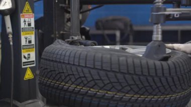 Bir araba tamircisi güvenlik kontrolü yapar ve atölyeye yeni lastikler takar.