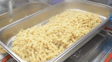 Şefler servis için tepsilere sıcak makarna dağıtırlar.