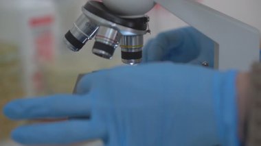 Biyolojik bir laboratuvarda mikroskop. Bir mikrobiyoloji uzmanı, bir maddeyi incelemek için bir biyoloji laboratuvarında mikroskop ayarlar.