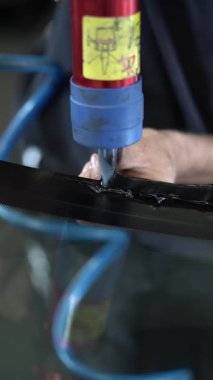 Dikey video. Araba camının yüzeyine dolgu macunu eşit olarak dağıtıyor.