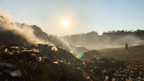 Burning pile of garbage at dump ground or landfill releasing toxic smoke in environment and polluting air. Sanitation Workers segregating garbage