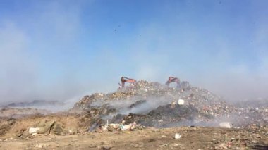 Çöplükte ya da atık sahasında yanan çöp yığını çevreye zehirli duman yayıyor ve havayı kirletiyor. Kazıcı ya da toprak taşıyıcı çöpü ayırır ya da taşır.