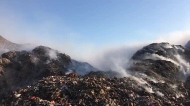 Çöplükte ya da atık sahasında yanan çöp yığını çevreye zehirli duman yayıyor ve havayı kirletiyor. Temizlik işçileri çöpleri ayırıyor