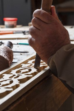An engraver embroidering various motifs on wood