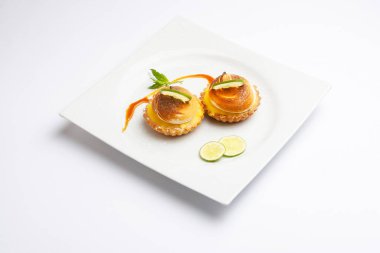 Cream cookies decorated with lemon and mint on a white plate