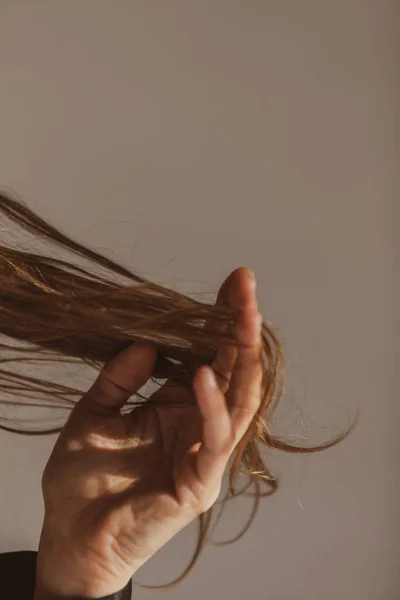 Bir Kadının Eli Uzun Saçlarına Dokunuyor Arka Planı Gri — Stok fotoğraf