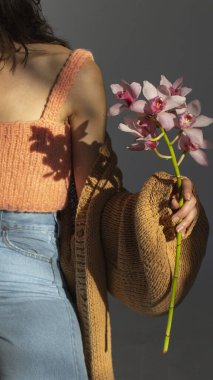 Güneş ışığında orkideleri tutan el.