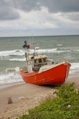 Souther Baltic sea coast, Northern Poland, Pomerania, sandy beach, dramatic sky, late winter time, fishing boat on the sand