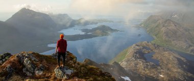 Hiker on the top of a cliff in Lofoten