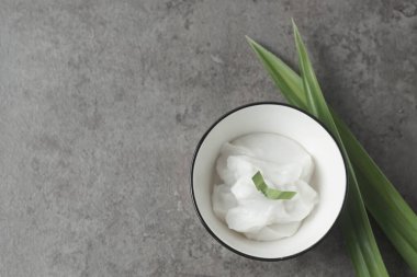 Bubur sum sum or Bubur merah putih.Traditional Indonesian dessert made from sweet glutinous rice, coconut milk, and pandanus leaf, topped with a sprinkle of red and white sugar.Closeup