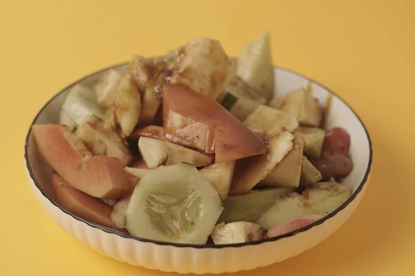 Rujak Buah taze tropikal meyvelerden oluşan bir Endonezya tatlısıdır. İçinde palmiye şekeri, demirhindi, biber, sarımsak ve tuzdan yapılan tatlı ve baharatlı bir sos var. Seçici odak, Yakın plan