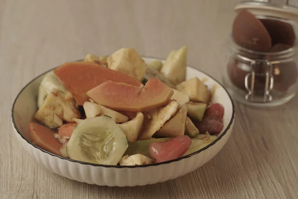 Rujak Buah taze tropikal meyvelerden oluşan bir Endonezya tatlısıdır. İçinde palmiye şekeri, demirhindi, biber, sarımsak ve tuzdan yapılan tatlı ve baharatlı bir sos var. Seçici odak, Yakın plan